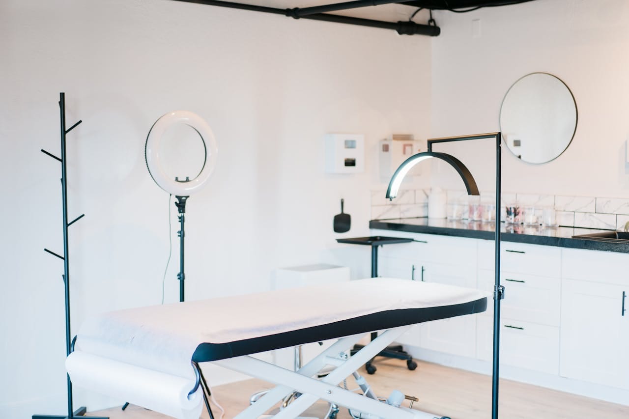 Bright and modern medical spa room featuring massage bed and studio lighting.